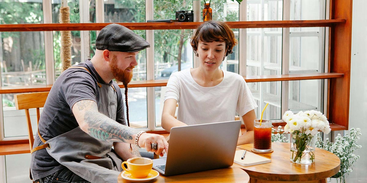 small business owner and marketer enjoying coffee and pointing at laptop screen